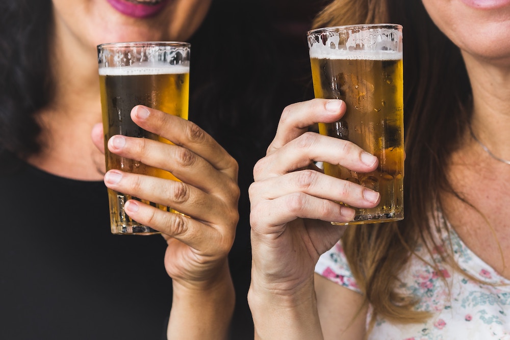 Two women hold up glasses of beer
